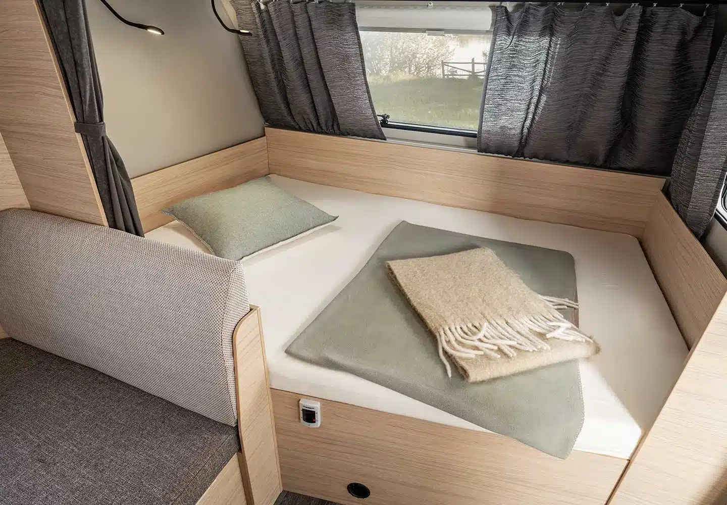 Schlafplatz mit Kissen und Decken im Interieur des WEINSBERG CaraLife Caravans