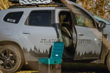 Portable Verschweißtoilette vor einem mit Dachgepäck und Dachzelt ausgestatteten Dacia Duster