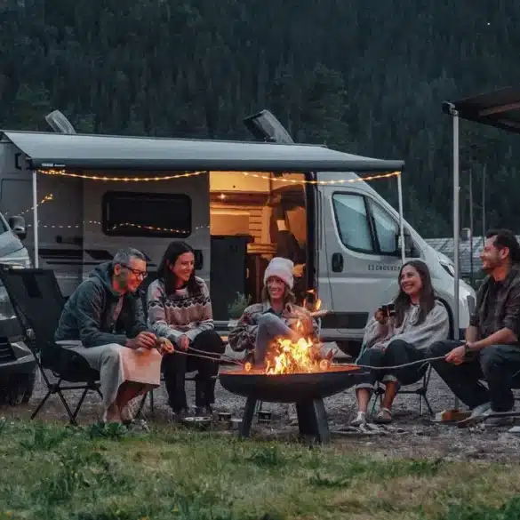 CROSSCAMP EXPLR Campervan mit geöffnetem Aufstelldach und Menschen beim Camping am Lagerfeuer