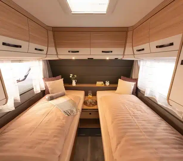 Einzelbetten im Innenraum des Dethleffs Summer Edition 460 EL Caravans mit hellem Holzdekor und Stauraumfächern