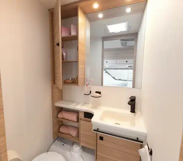 Innenansicht des Badezimmers im Dethleffs Summer Edition 460 EL Wohnwagen mit Waschbecken, Spiegelschrank und Ablagefächern