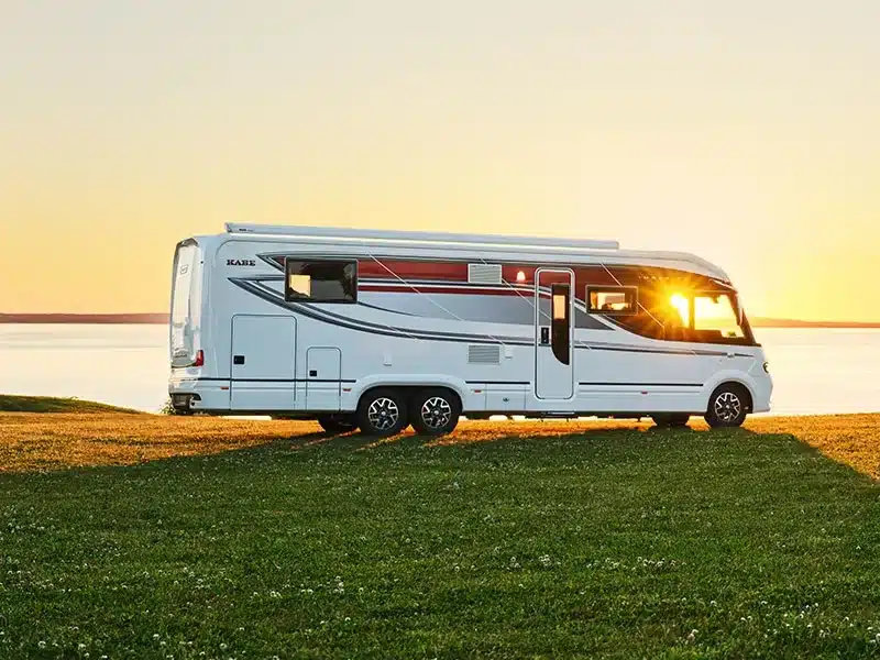 KABE Imperial i790 LGB Wohnmobil auf einer Wiese vor einem See, Sonnenuntergang im Hintergrund