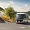 Niesmann+Bischoff iSmove 2027 Reisemobil fährt auf einer Straße durch hügelige Landschaft.