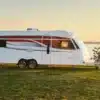 KABE Imperial 1000 TDL Caravan auf einer Wiese mit Blick aufs Wasser bei Sonnenuntergang