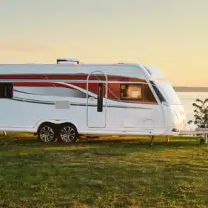 KABE Imperial 1000 TDL Caravan auf einer Wiese mit Blick aufs Wasser bei Sonnenuntergang