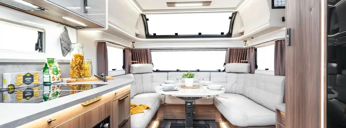 Geräumiger Wohnbereich und Küche im KABE Imperial 1000 TDL Wohnwagen mit heller Möblierung und Esstisch.