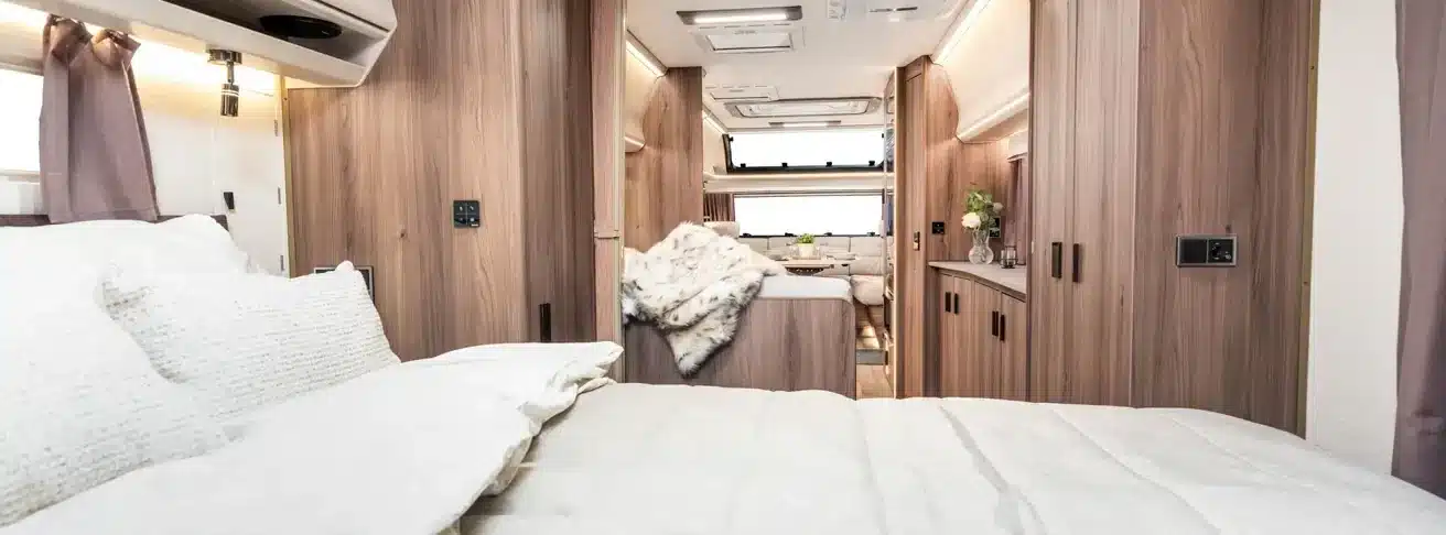 Geräumiger Innenraum des KABE Imperial 1000 TDL mit großem Bett, Holzdekor und Blick durch den Caravan