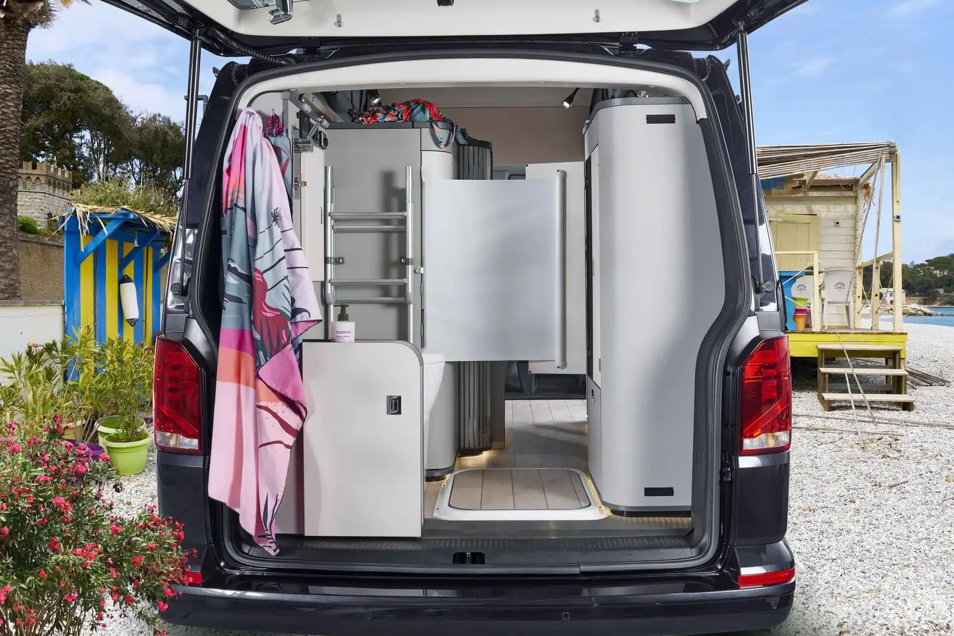 Blick von hinten ins Bad und den Innenraum des Westfalia Kepler One Campervans, kompakter VW-Ausbau am Strand.
