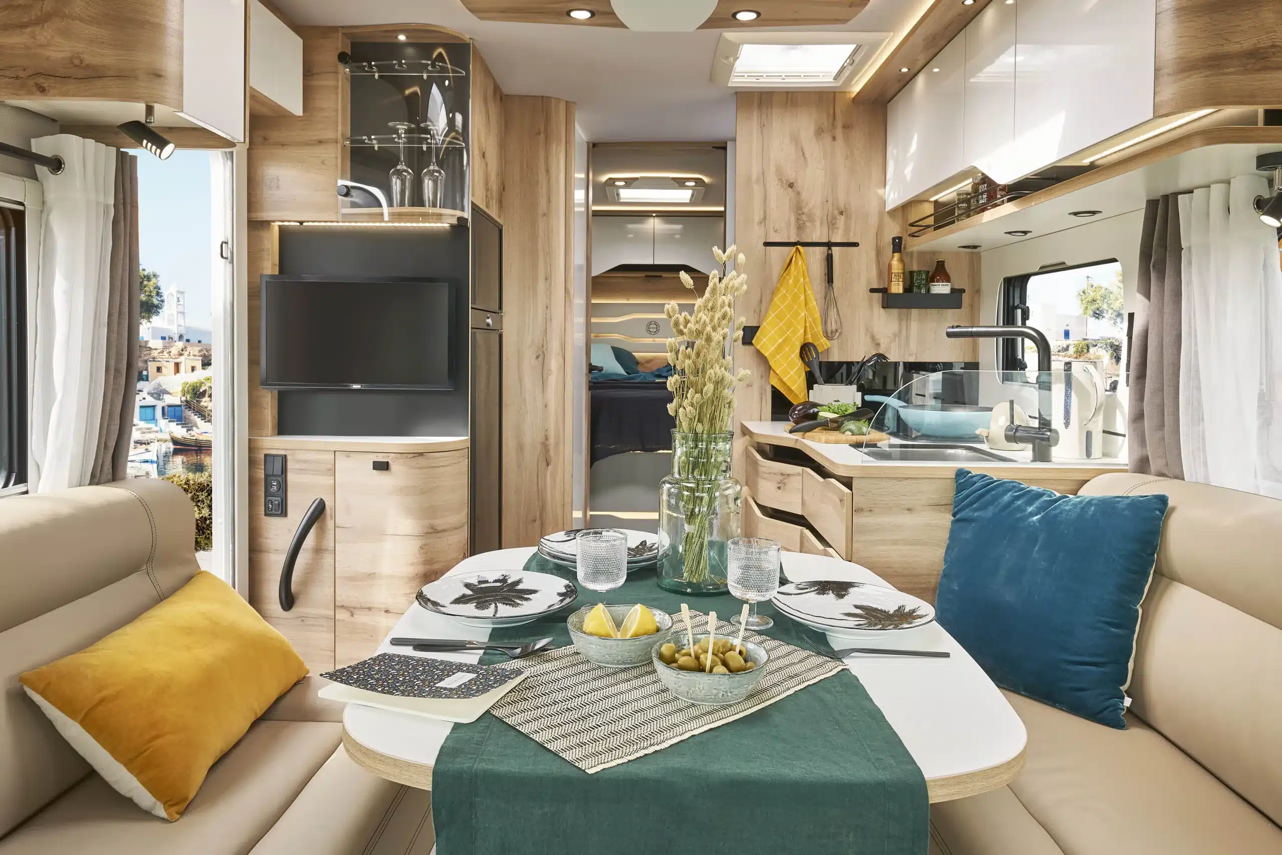 Moderner Wohnbereich und Küche im Le Voyageur LV7.5CF Reisemobil mit großzügigem Essplatz und stilvoll gedecktem Tisch.