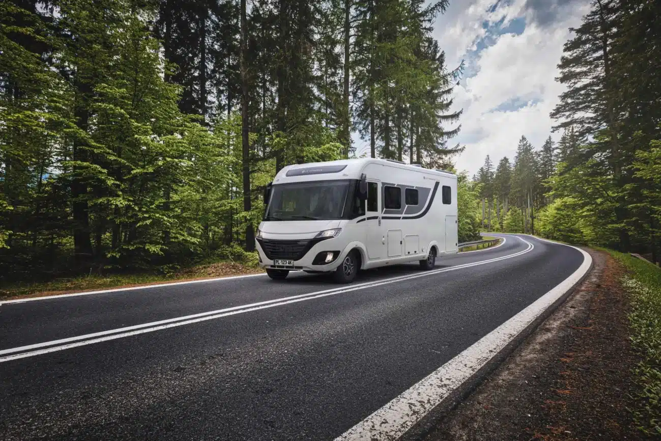 Le Voyageur LV7.5CF Reisemobil fährt auf einer Landstraße durch Wald.