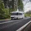 Le Voyageur LV7.8GJF Reisemobil auf einer kurvigen Landstraße im Wald, Außenansicht