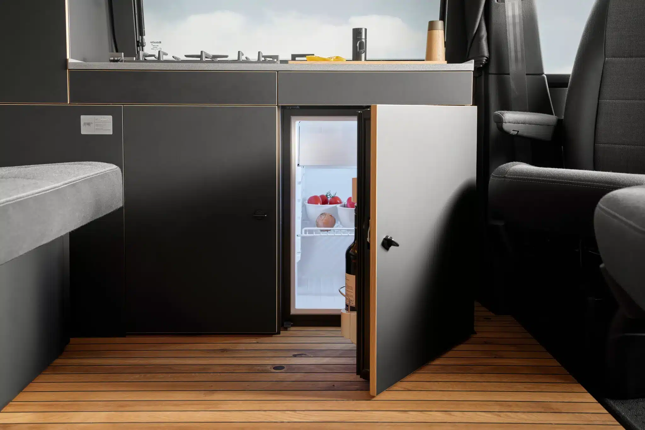 Geöffneter Kompressor-Kühlschrank und Küchenzeile mit Gaskochfeld im Camperausbau Moormanns Holzklasse 2.0