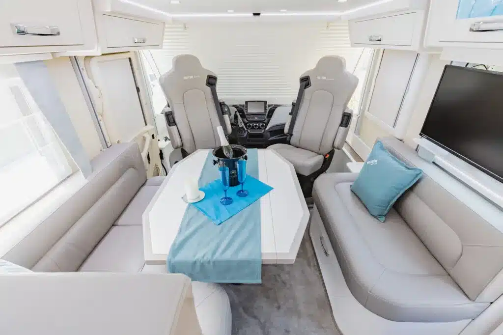 Innenraum vom NOTINLINER 940G mit Sitzgruppe und Tisch, modernes Wohnmobil-Design.