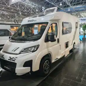 Weißes ROADfans-Reisemobil mit geöffneter Seitentür auf einem Messestand