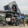 Yakima SkyPeak HD Dachzelt montiert auf einem Pick-up mit Vanlife-Ausrüstung und zwei Personen beim Camping.