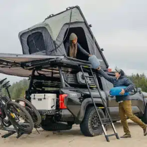 Yakima SkyPeak HD Dachzelt montiert auf einem Pick-up mit Vanlife-Ausrüstung und zwei Personen beim Camping.