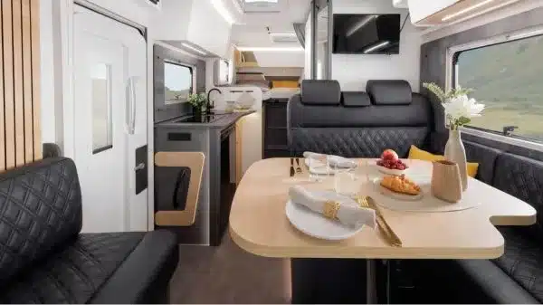 Blick in den Wohn- und Essbereich des Ahorn Camp T 690 ECLIPSE Reisemobils mit schwarzer Polsterung und gemütlicher Dinette