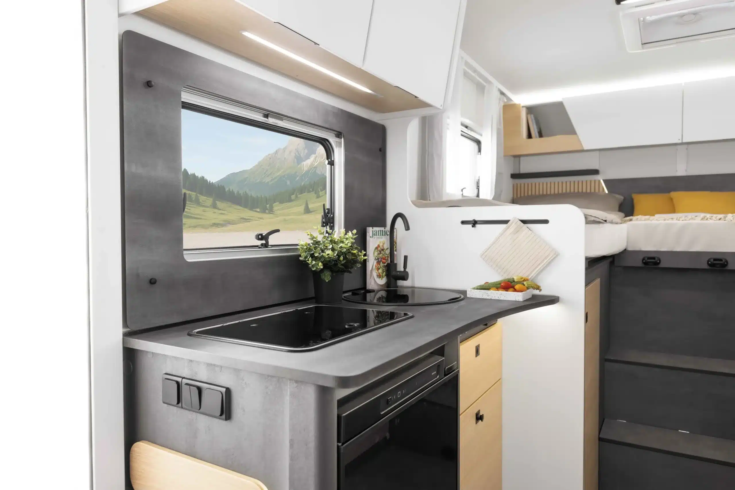 Küchenzeile und Schlafbereich im Ahorn Camp T 690 ECLIPSE Reisemobil, modernes Interieur mit dunklen Akzenten.