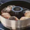 Mobiler Backofen VAMO® mit frisch gebackenen Brötchen auf einem Campingkocher.