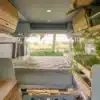 Innenansicht eines elektrischen VAN-Jorn CHARGE Campers mit Bett, Stauraum und modularer Küche