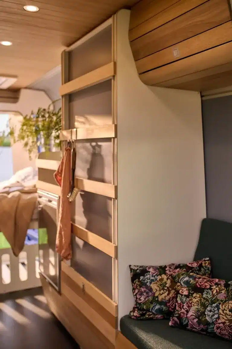 Innenraum eines VAN-Jorn CUSTOM Campervans mit modularen Holzelementen, Sitzpolstern und wohnlicher Atmosphäre.