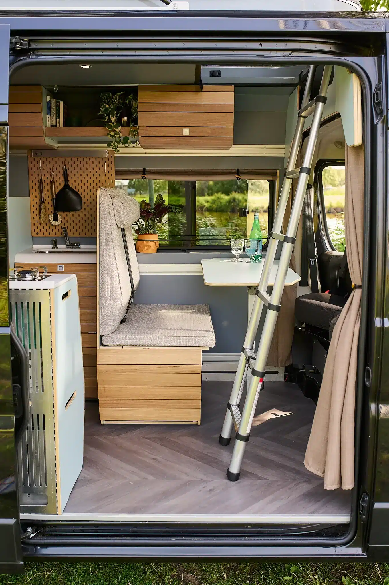 Blick in den Innenraum eines VAN-Jorn Family Campers mit Sitzbank, Tisch, Leiter und Stauraum