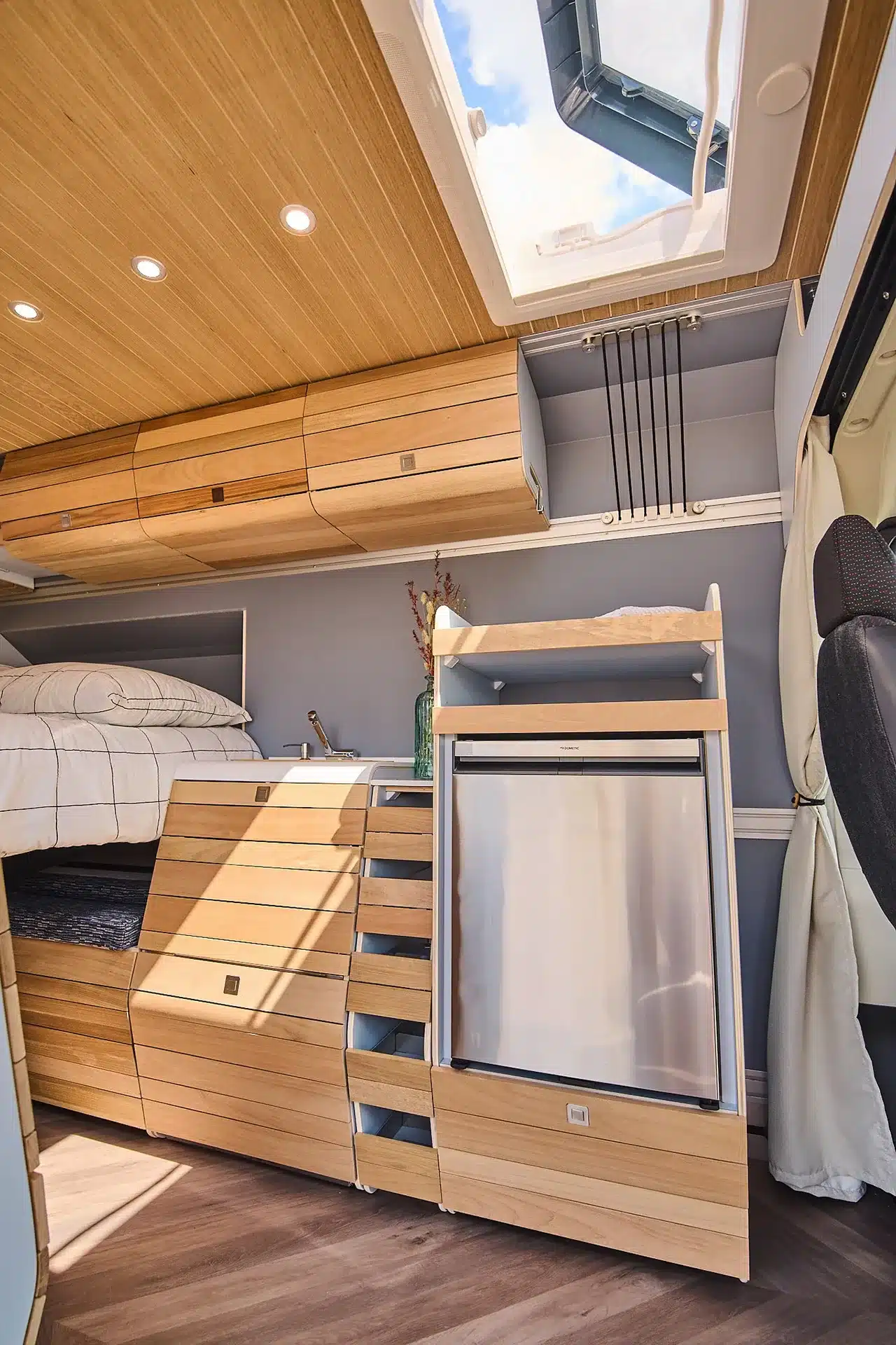 Modularer Innenausbau eines VAN-Jorn Reisemobils mit Bett, Schränken und Küchenmodul unter einer Dachluke