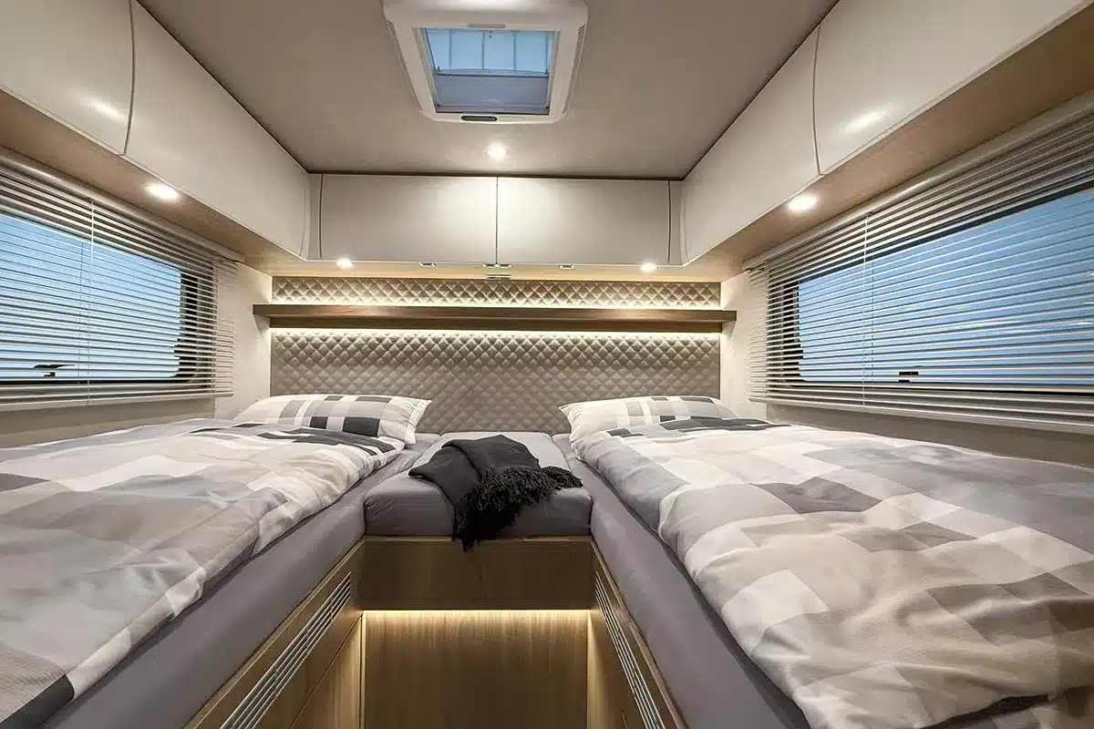 Innenansicht des Schlafbereichs im VARIO Star 800 Reisemobil mit zwei separaten Betten, Holz- und Weißoptik sowie großen Fenstern.