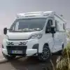WEINSBERG CaraCompact Reisemobil steht auf einer Landstraße, umgeben von Natur