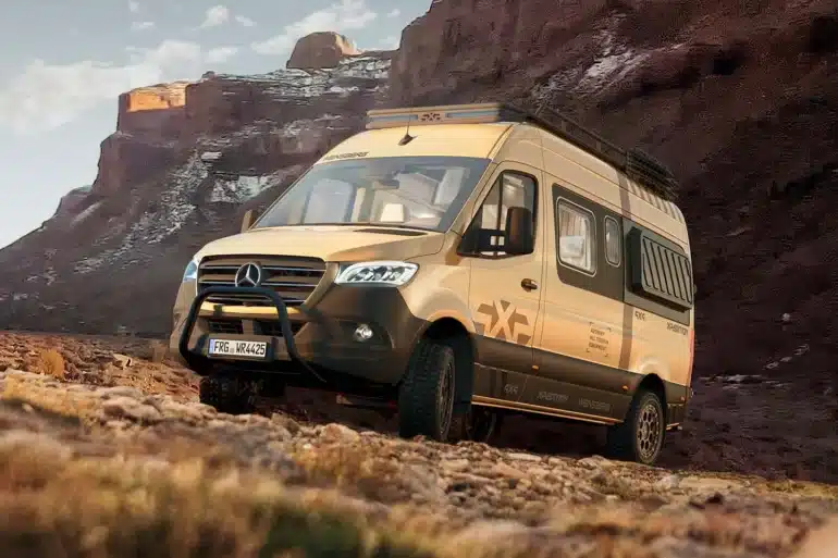 WEINSBERG X-PEDITION 600 MQ Camper Van mit Mercedes-Benz Chassis, All-Terrain-Bereifung und Frontschutzbügel im Offroad-Einsatz vor Felskulisse.