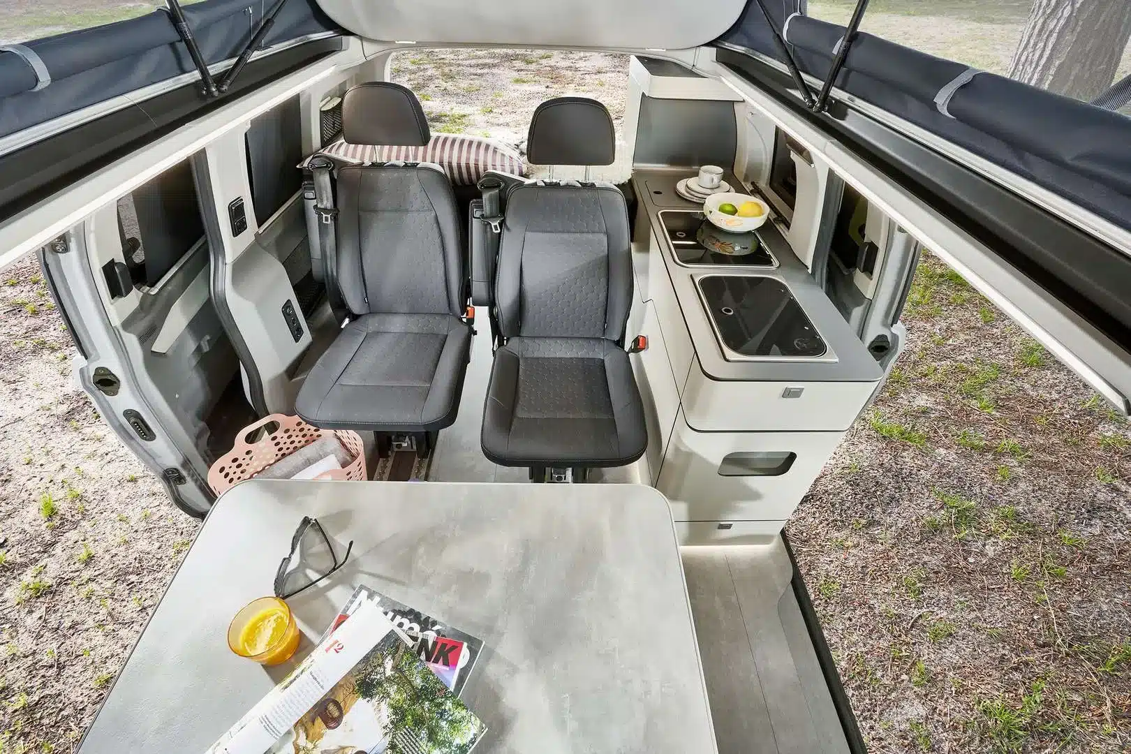 Innenansicht des Westfalia Club Joker Urban Campervans mit zwei Einzelsitzen, Tisch und kompakter Küchenzeile