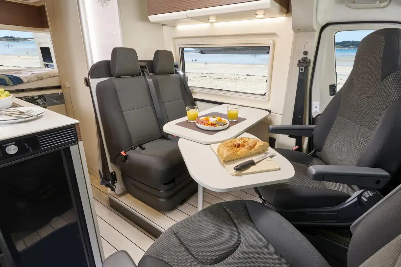 Innenraum des Westfalia Columbus 600 D mit Sitzgruppe, Tisch und Blick aufs Heckbett.