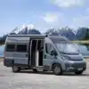 Westfalia Columbus 640 E Kastenwagen, geparkt vor See und Bergen, Seitenansicht mit geöffneter Tür.