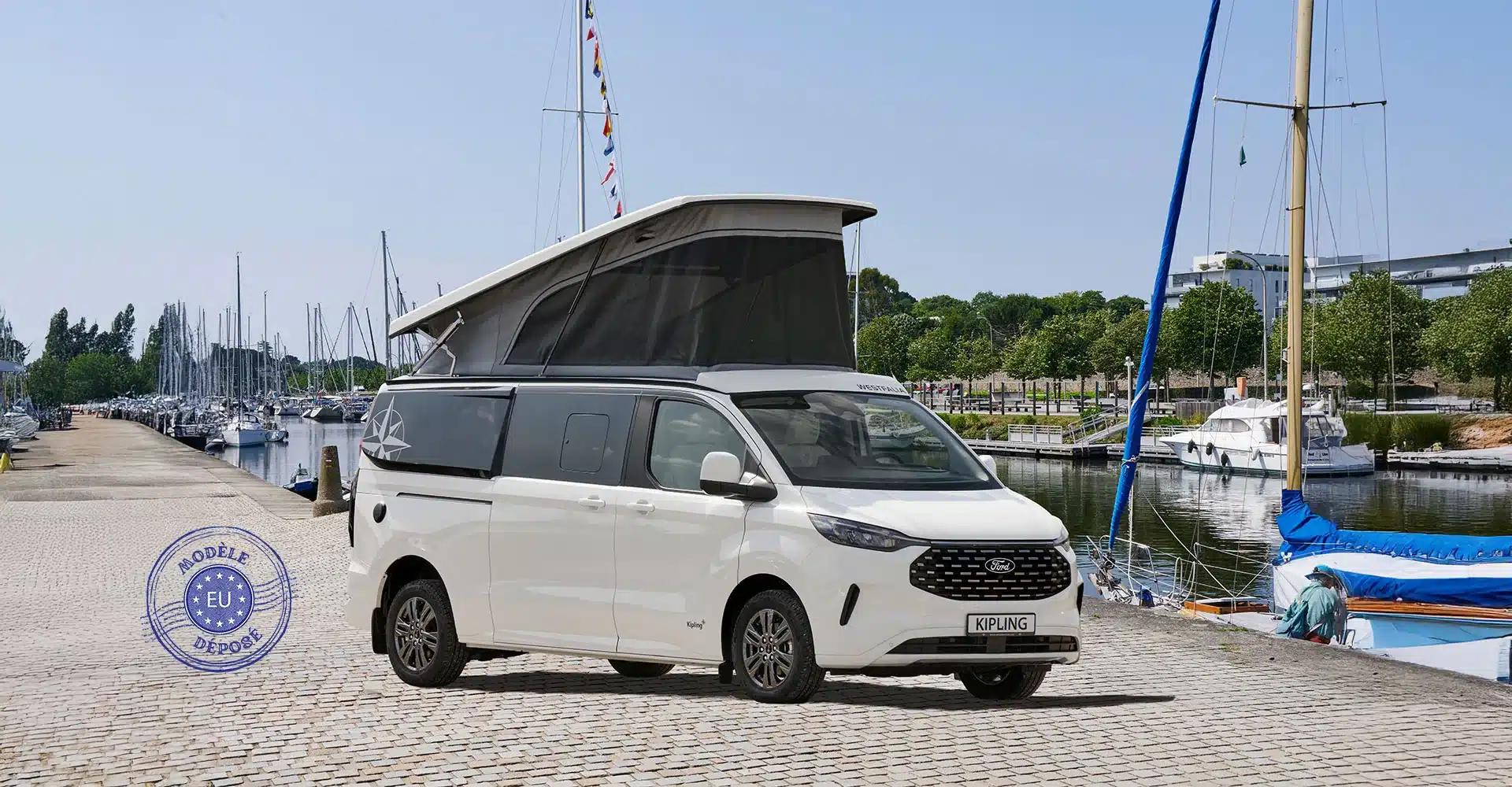 Westfalia Kipling Campervan mit geöffnetem Aufstelldach am Kai, im Hintergrund Boote und Yachthafen.