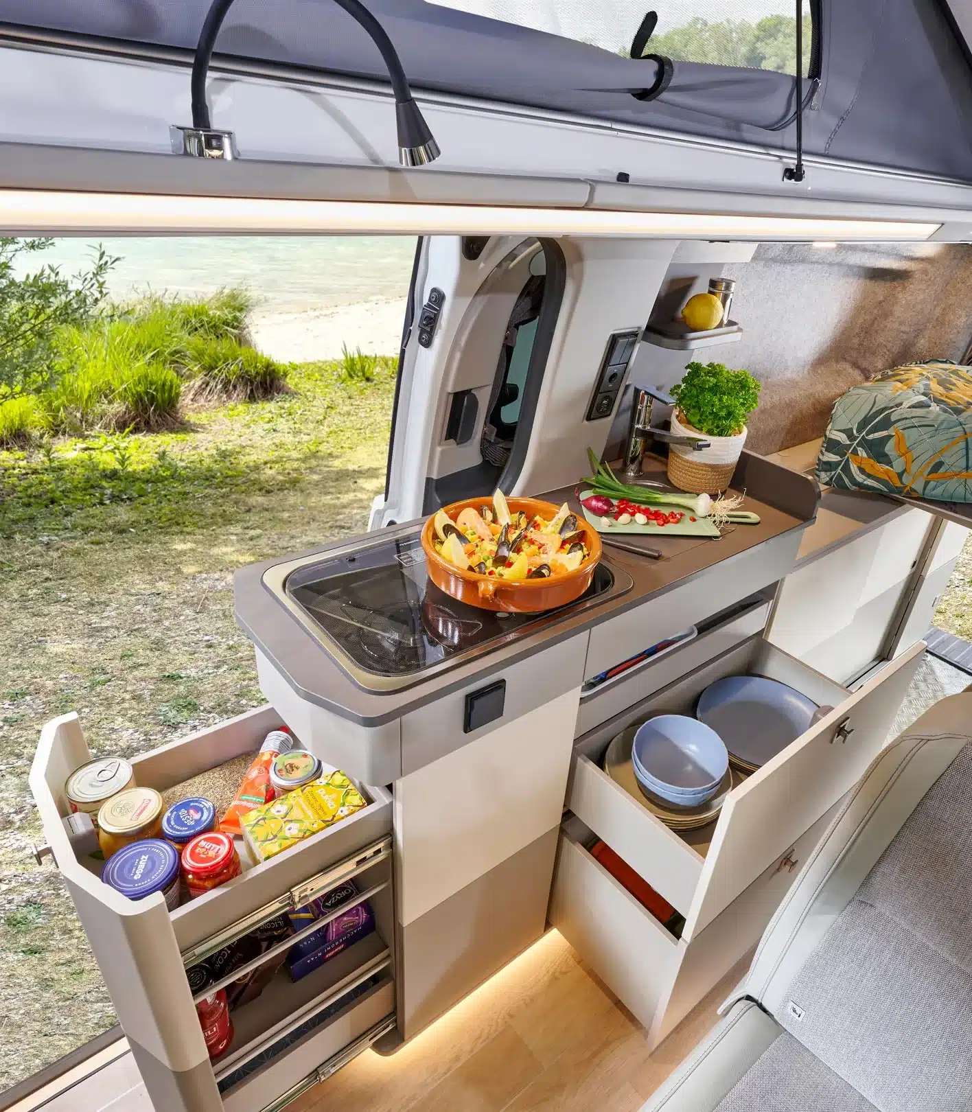 Küchenbereich mit Kochfeld, Arbeitsfläche und geöffneten Staufächern im Westfalia Kipling Campervan.