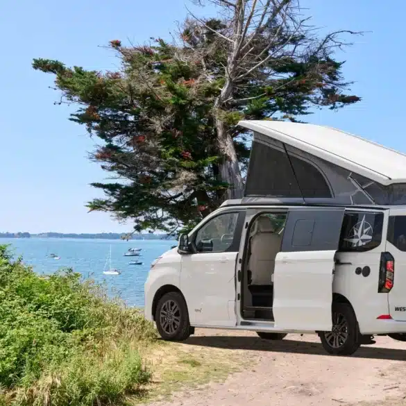 Westfalia Kipling Campervan mit geöffnetem Aufstelldach an einem Seeufer, im Hintergrund Wasser und Bäume