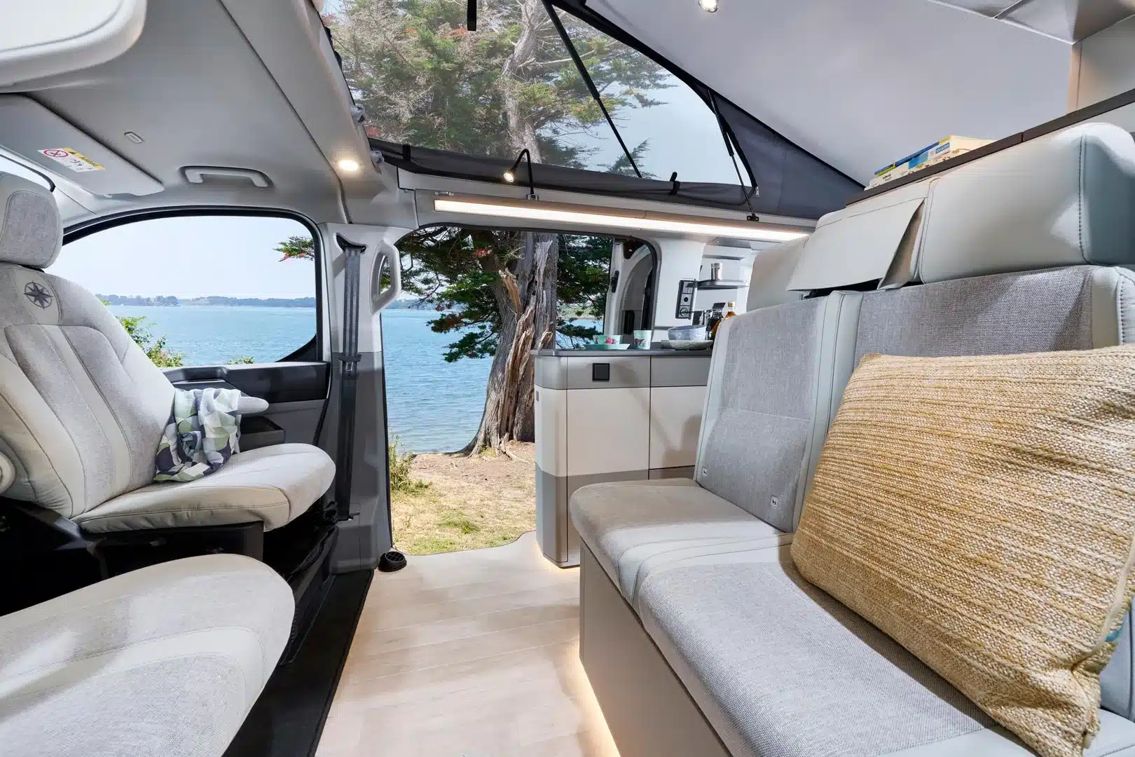 Innenraum des Westfalia Kipling Campervans mit Sitzbereich, Küche und Panoramadach an einem Seeufer