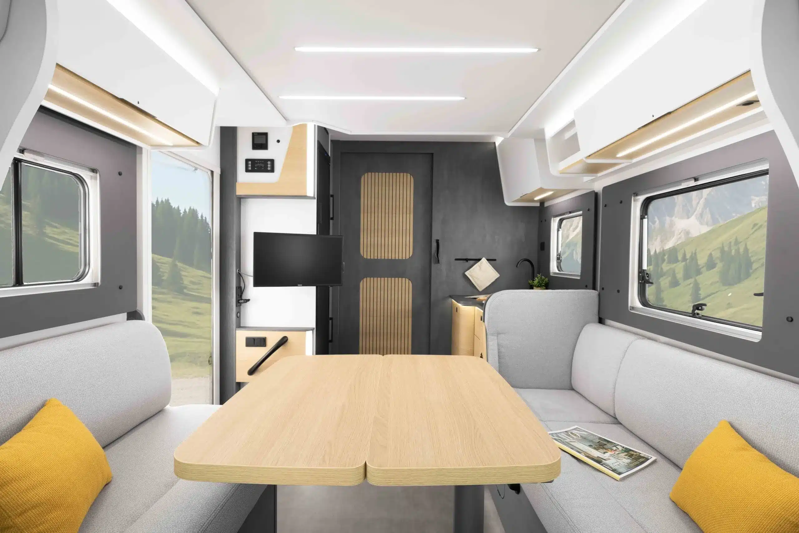 Innenraum des Ahorn Camp T 640 mit Dinette, Tisch, Sitzpolstern, Oberschränken und großen Seitenfenstern