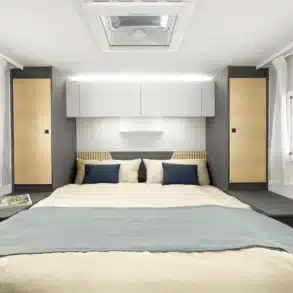 Queensbett im Ahorn Camp TQ 740 mit moderner Innenausstattung, flankiert von Fenstern und Stauraum.