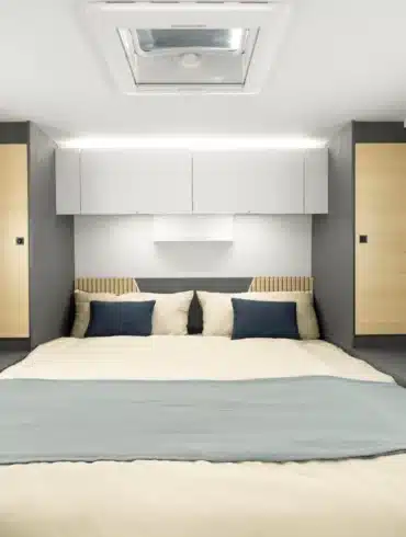 Queensbett im Ahorn Camp TQ 740 mit moderner Innenausstattung, flankiert von Fenstern und Stauraum.