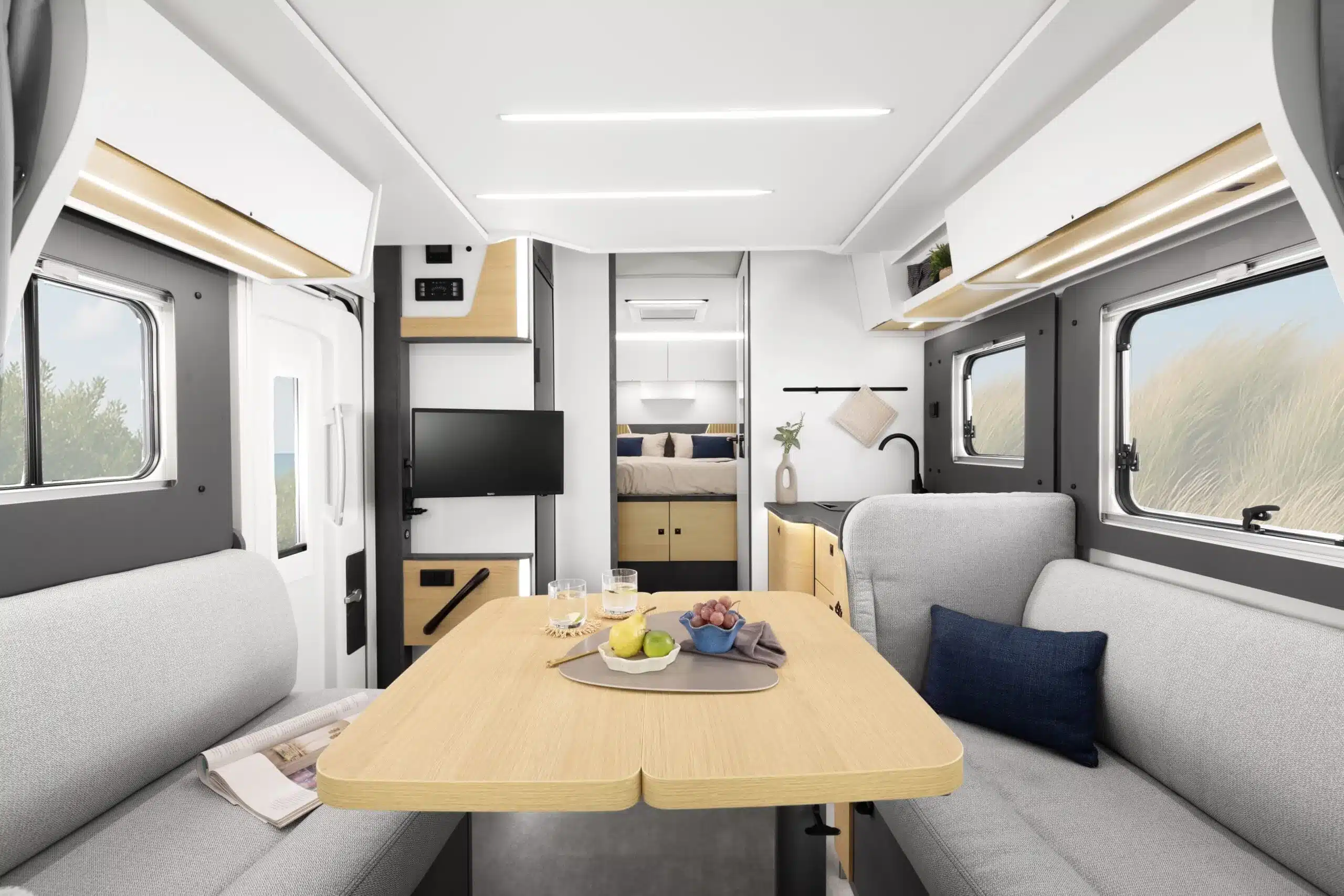 Innenansicht des Ahorn Camp TQ 740 Reisemobils mit großzügigem Wohnraum, Dinettentisch, Küche und Zugang zum Queensbett.