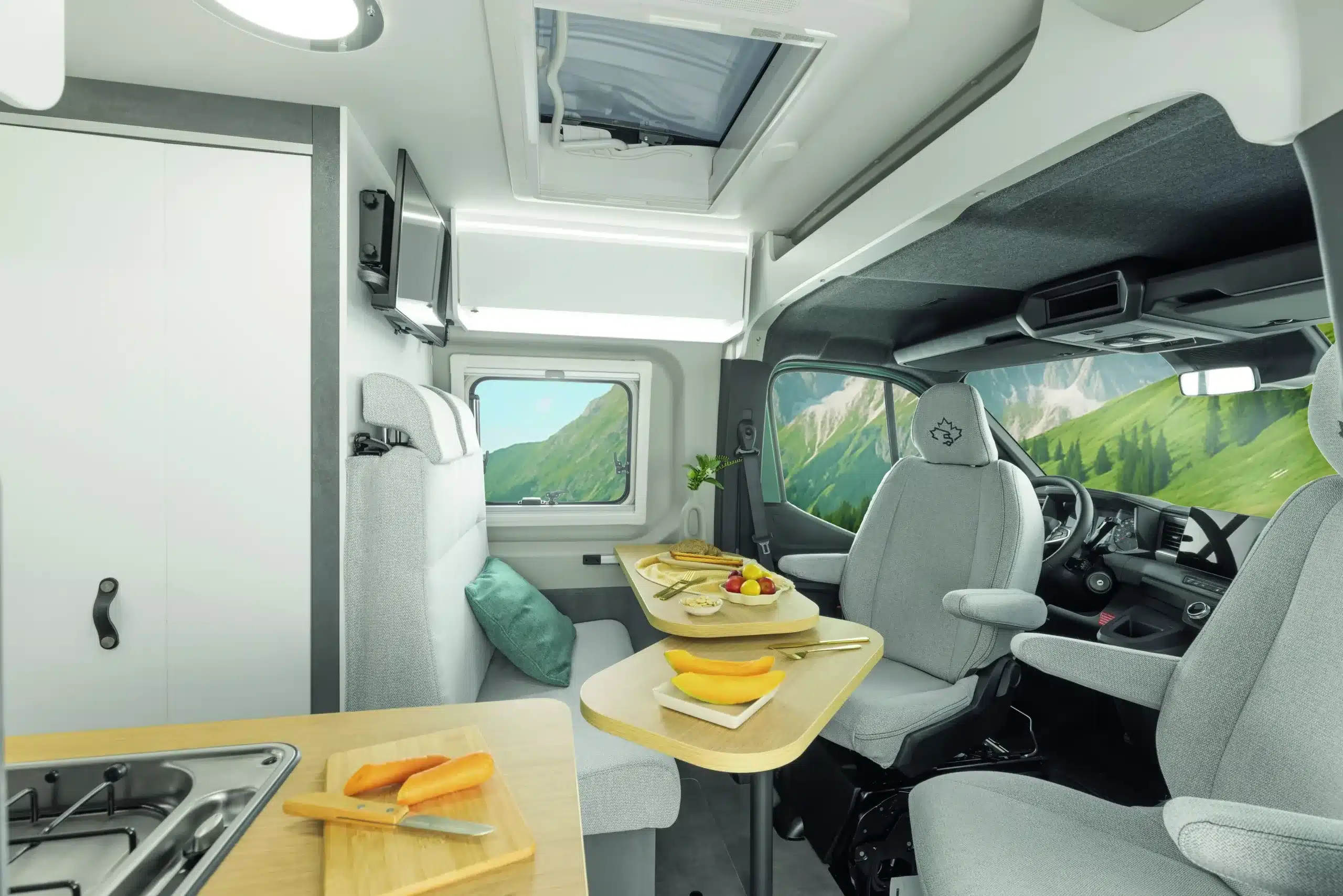 Innenansicht des Ahorn Camp Van 630 mit Sitzgruppe, Tisch und Küchenzeile, Tageslicht durch Dachluke und Fenster.