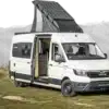 Weißer Vannado Altiplano Campervan mit Solardach und geöffneter Schiebetür vor einer Berglandschaft
