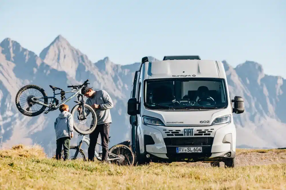 Weißer Sunlight CLIFF 602 Adventure Camper Van mit zwei Mountainbikes vor Bergen