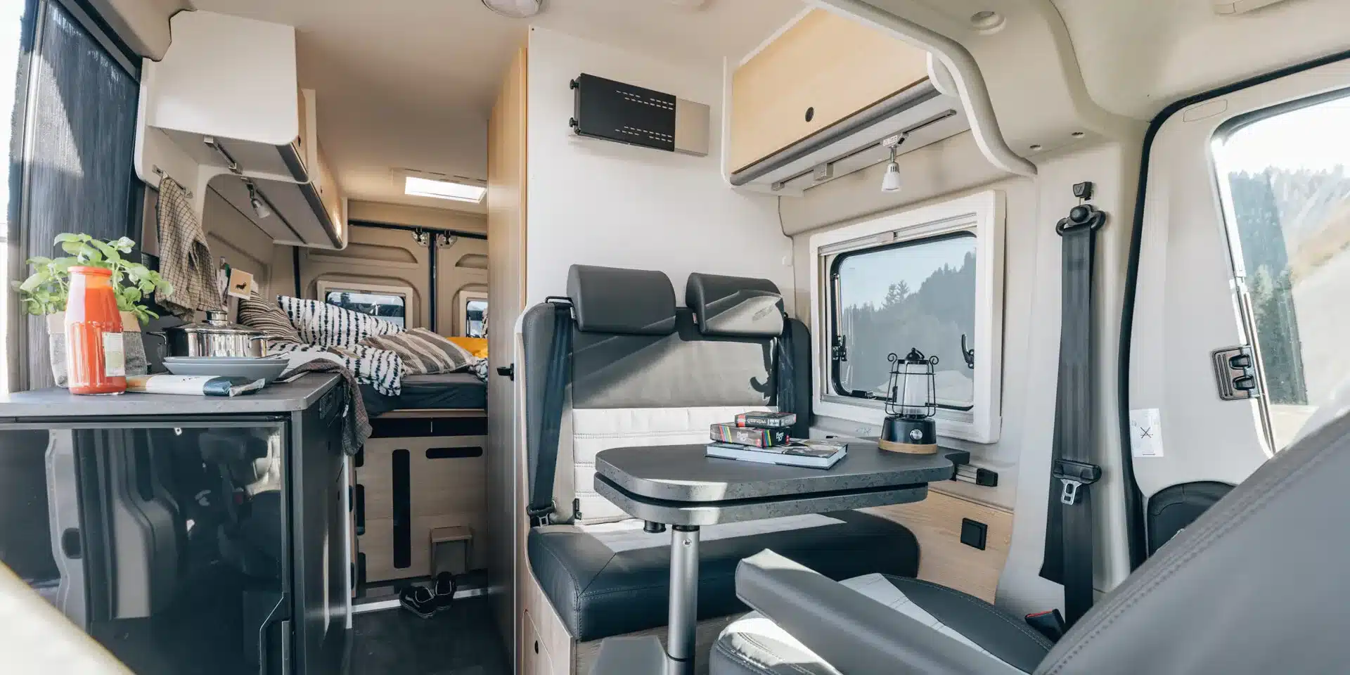 Innenraum eines Sunlight CLIFF Adventure Camper Vans mit Sitzgruppe, Küche und Bett
