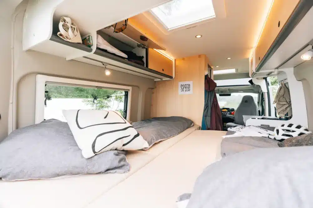 Blick in den Innenraum eines Sunlight CLIFF X Camper Vans mit großem Bett, Stauraumfächern und Dachfenster.