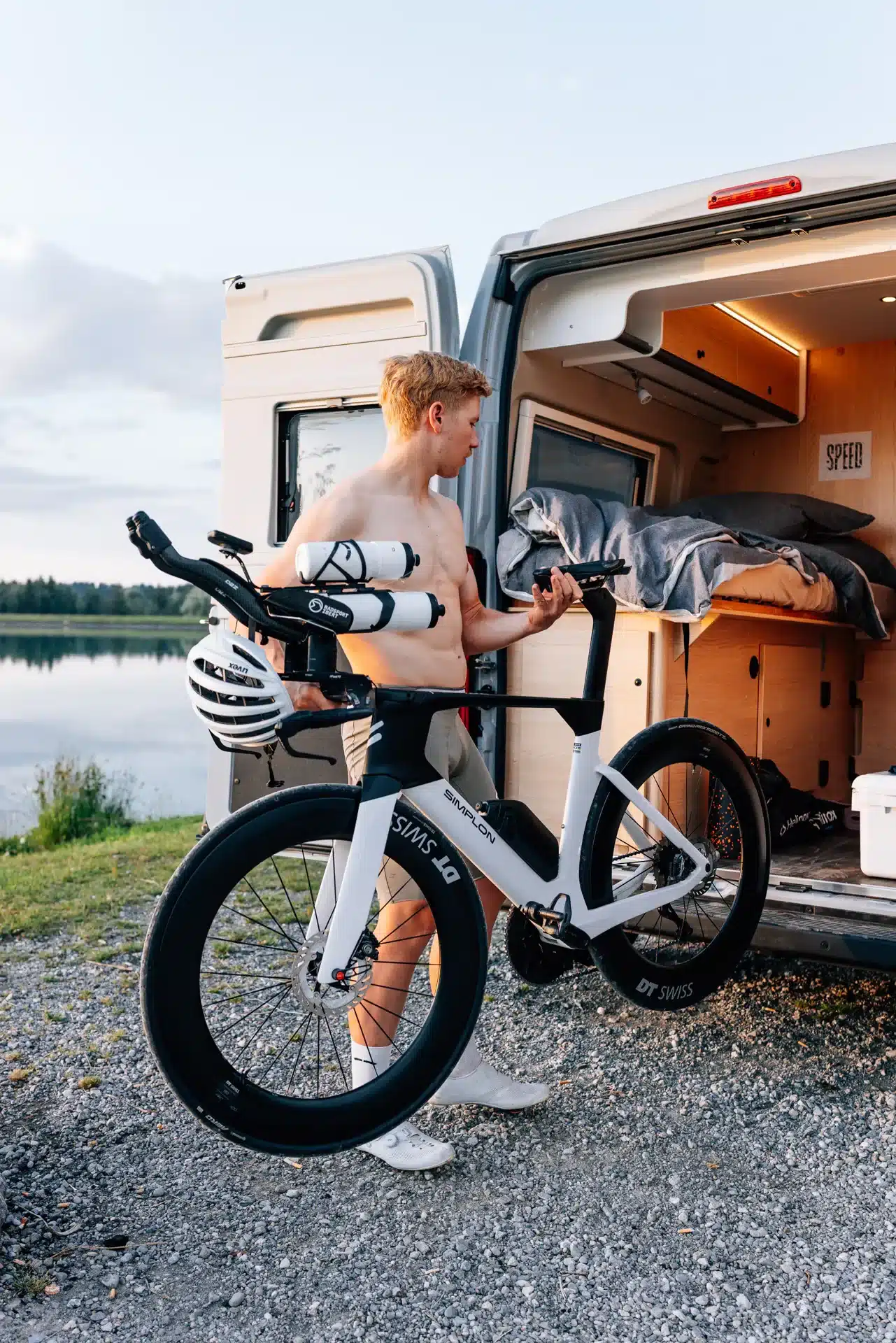 Sunlight CLIFF X Camper Van geöffnet, mit junger Mann und Fahrrad am See