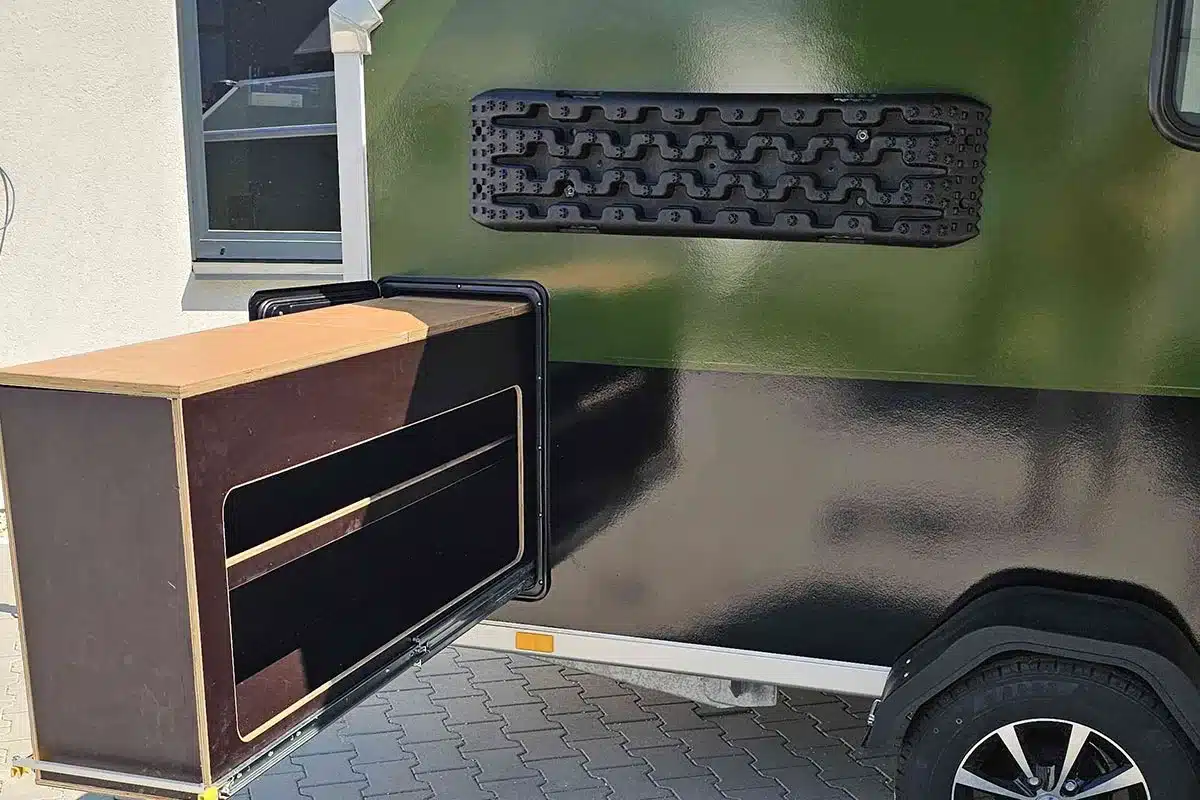 D’ Camper mit ausgezogenem Küchenmodul und seitlicher Campingausstattung