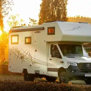 Außenansicht des DOPFER 422 A Reisemobils vor herbstlicher Kulisse bei Sonnenaufgang.
