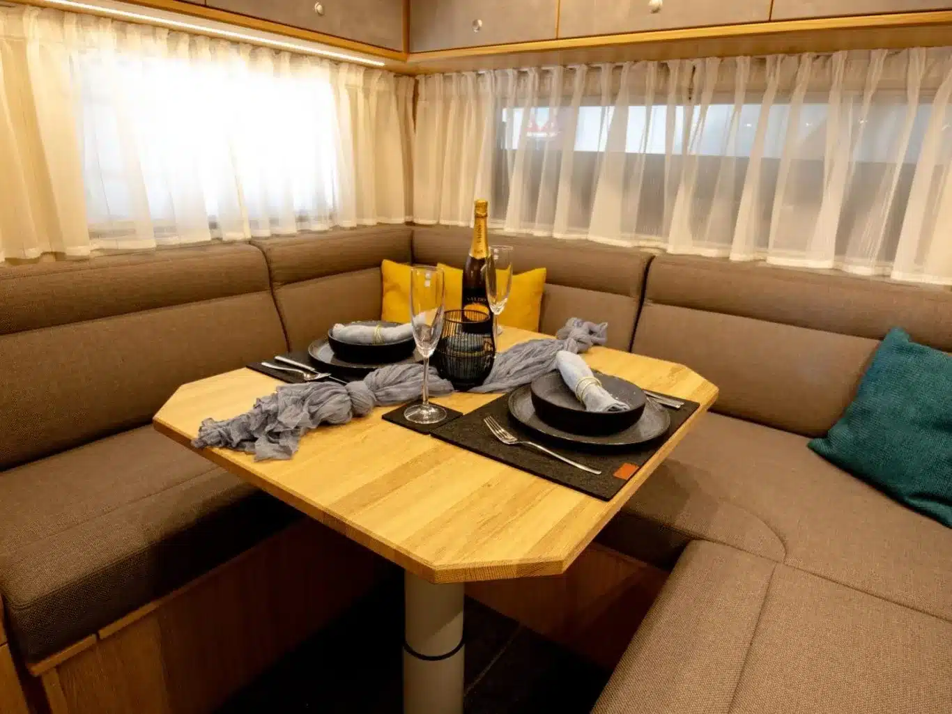 Sitzgruppe mit Holztisch und gedecktem Tisch im Innenraum des DOPFER 432 A Reisemobils